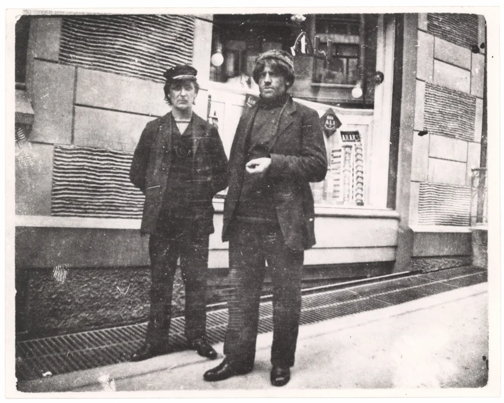 Mikkelsen og Iversen standing on a pavement next to a building look to the camera.